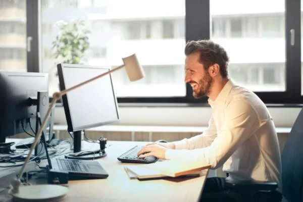 Happy men woking on the computer in the office with desk lamp