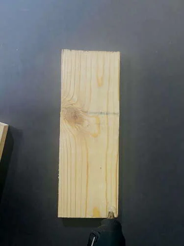 Wooden piece of the DIY lamp frame with glue being applied